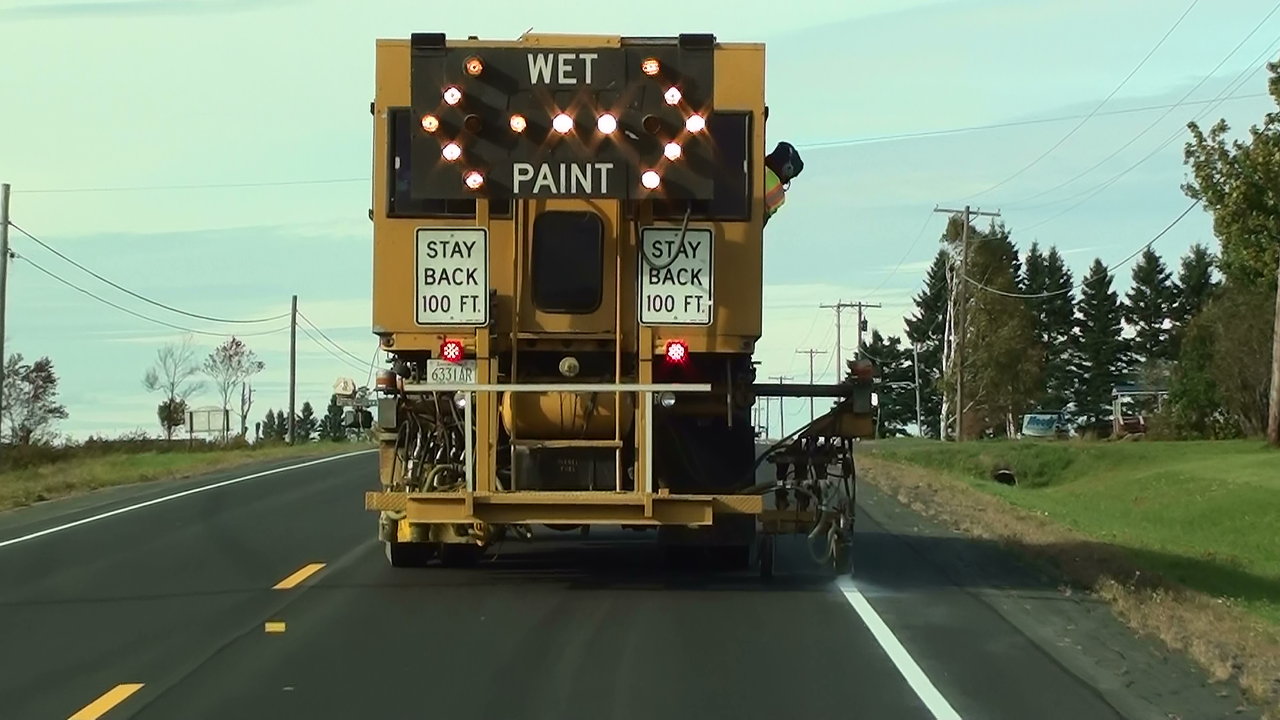 Sir Lines-A-Lot pavement marking truck with WET PAINT arrow board on the road